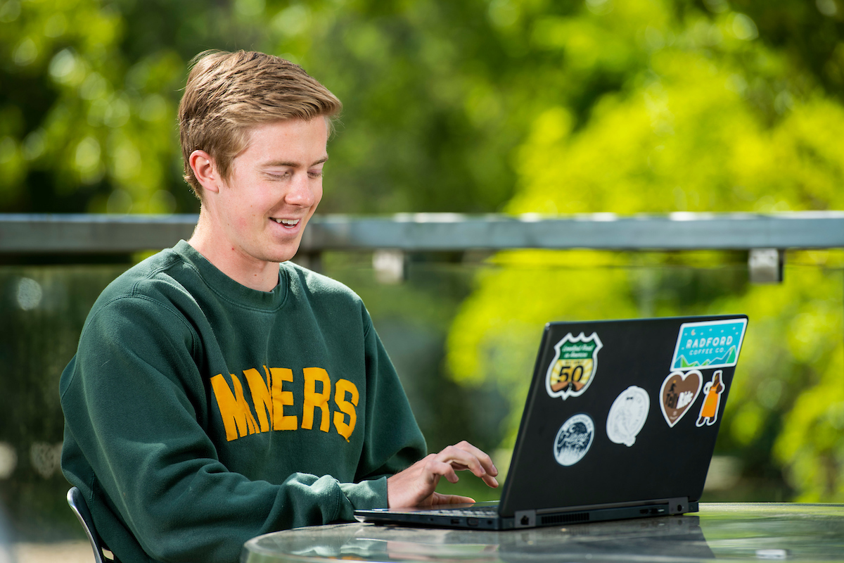 photo of a young man using a laptop outside